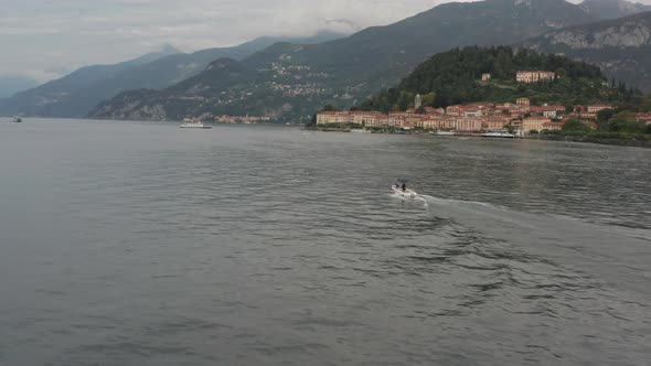 Drone following boat on a vast and beautiful lake with a historical city in the background