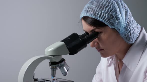 Lab Assistant Looks at Material Sample Through Microscope