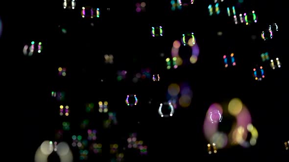 Soap Bubbles Fly in the Air and Shimmer in Different Colors. Black Background