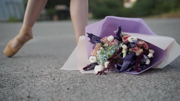 Closeup of Flower Lying on Asphalt As Slim Ballerina in Yellow Pointes Hitting Bouquet Away