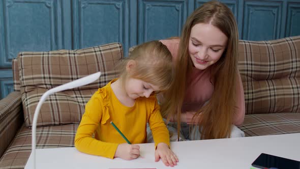 Lovely Mother Babysitter Teacher Helping Kid Daughter with Homework Learning Drawing at Home