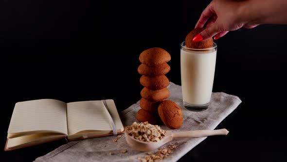 Oatmeal Cookies Laid Out in a Stack a Woman's Hand Soaks Cookies in a Milk Glass