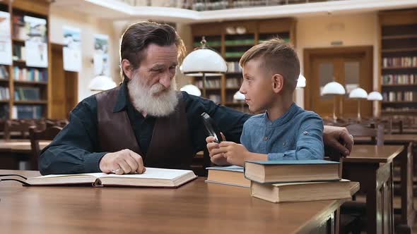 Handsome Wise Bearded Grandfather Spending Time in Library with His Teen Grandson