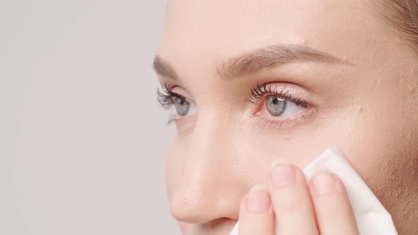 Young Beautiful Woman Wiping Her Face with Oil Absorbing Paper Close Up