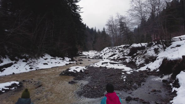 Two girls are standing near a mountain river. winter. aerial drone shot.