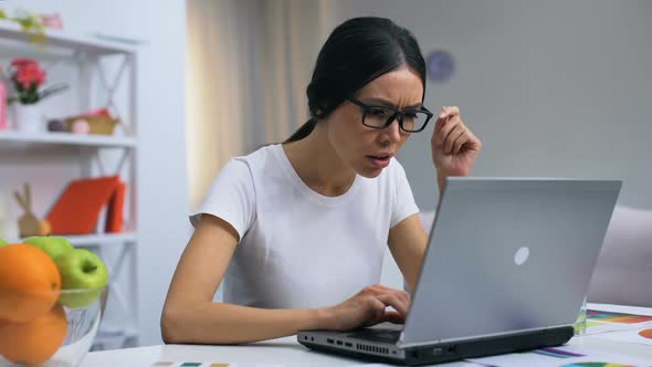 Overworked Female Freelancer Taking Eyeglasses Off, Working on Laptop, Overtime