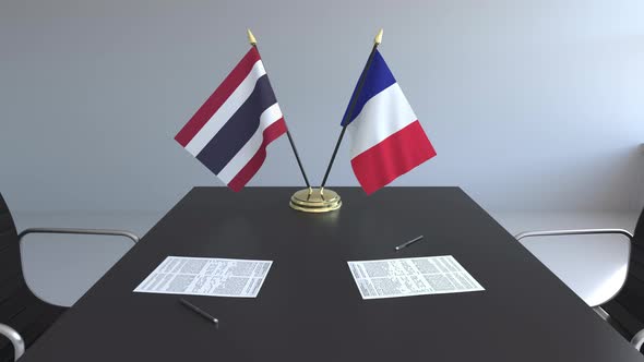 Flags of Thailand and France and Papers on the Table