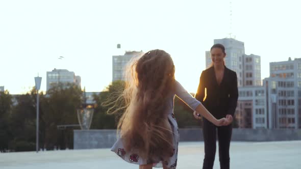 Happy Teen Girl in Dress and Blonde Long Hair Running To Her Stylish Mother and Jumping Into Her