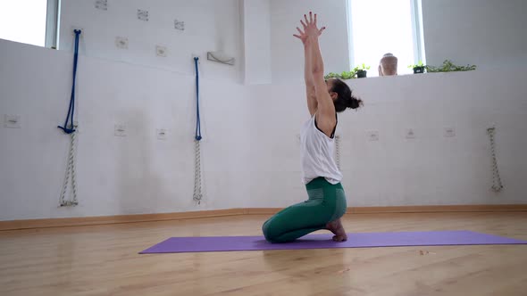 Woman showing Cactus and Eagle Arms poses on yoga mat