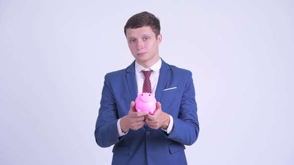 Happy Young Handsome Businessman Giving Piggy Bank