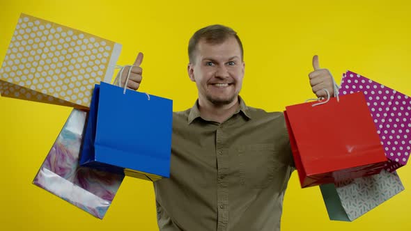 Man Raising Shopping Bags, Looking Satisfied with Purchase, Enjoying Discounts on Black Friday