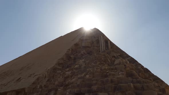 Eroded Bent Pyramid in Dahshur, Egypt with the sun shining at the top.