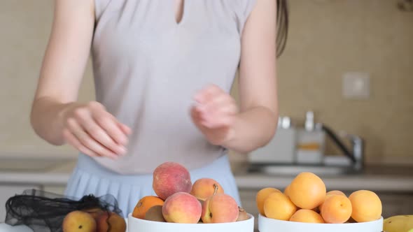 Woman Puts Ripe Fruit in a Plate in the Kitchen