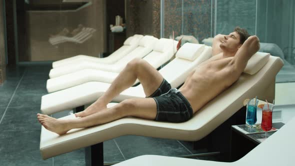 Sporty Man Relaxing at Wellness Resort. Sexy Guy Lying on Recliner in Hotel Spa.