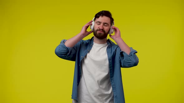 The Man Enjoys the Music with His Big White Wireless Headphones and Dances