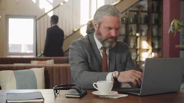 Portrait of Senior Businessman with Laptop in Restaurant