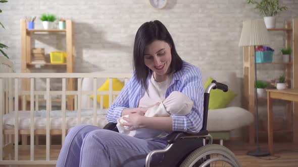 Portrait of a Young Disabled Woman and a Newborn Looking at the Camera and Smiling