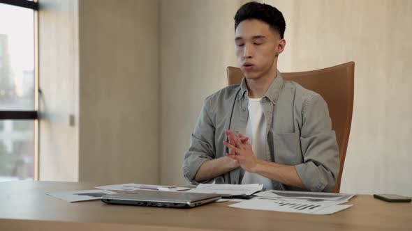 Asian Employee Closes Laptop Breathing Out and Relaxing