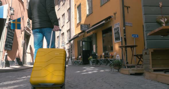 Back View Of A Traveling Man Walking With Suitcase