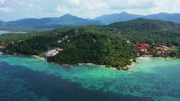 Tropical beach, luxury accommodation, palm trees covering the hills and mountains.