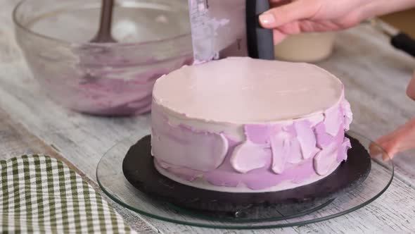 The process of decorating a cake with purple cream cover