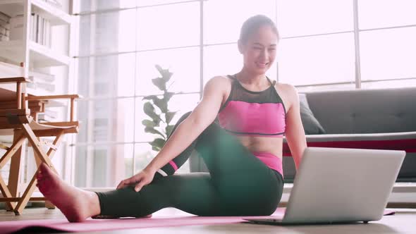 Asian girl is practicing online yoga from home.