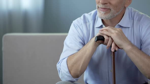 Happy Old Male Sitting on Sofa with Walking Stick and Relaxing, Retirement