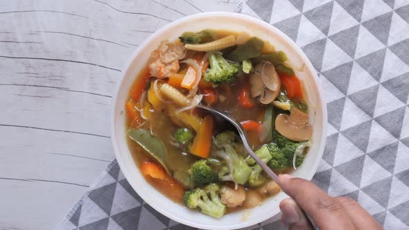 Top View Man Hand Preparing Vegetable Soup in a Bowl 