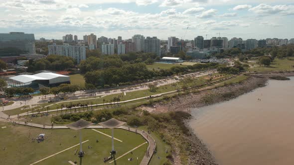 Aerial view of Vicente Lopez coastal walk with buildings and cloudy sky behind. Dolly in