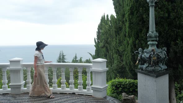 Elegant Woman Walking in Aivazovsky Park with Black Sea on Background, Crimea