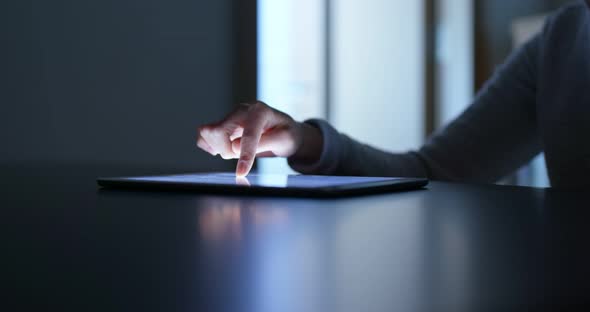 Woman finger touch on tablet computer at home in the evening