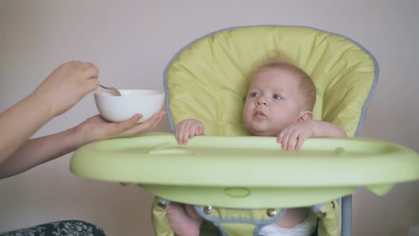 Mother Gives Small Son Wholesome Porridge in Highchair Close