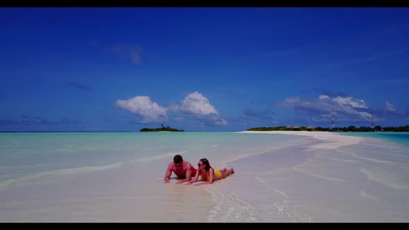 Teenage lovers posing on relaxing bay beach wildlife by blue green water with white sand background 