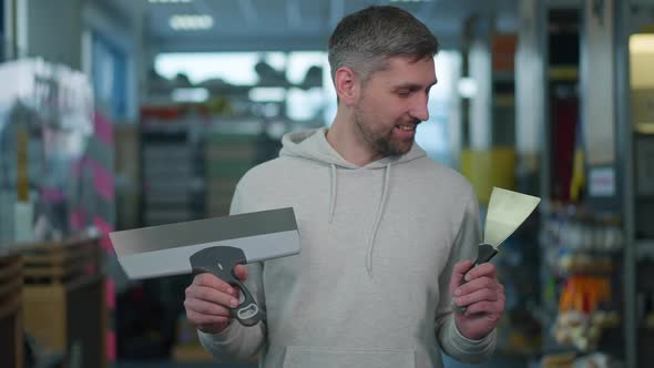 Bearded Caucasian Man Choosing Putty Knife in Hardware Store