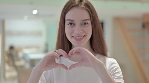 Portrait of Redhead Young Woman Making Heart Shape with Hands