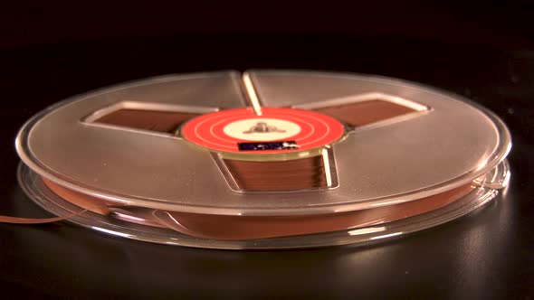 Reel to reel tape rotating before black background