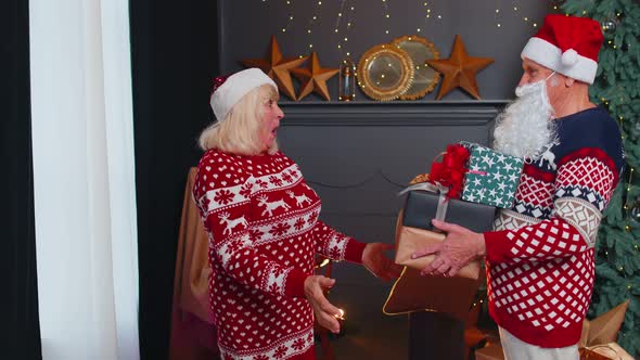 Grandfather Santa Claus Gifting Christmas Present Box to Surprised Grandmother Senior Couple Family