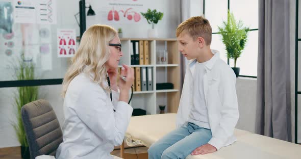 Female Pediatricain Examining Heartbeat and Lungs of  Boy During Scheduled Visit to Clinic