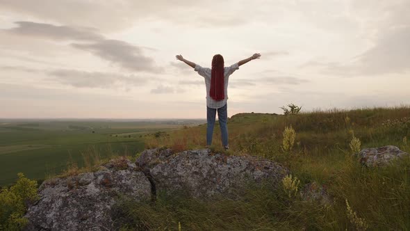 Girl in Plaid Shirt Raises Her Hands to the Sky Sunset