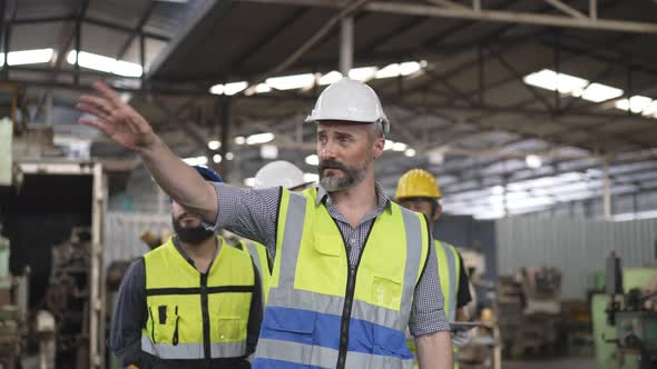 Male engineer foreman walking and explaining project to group of mechanic