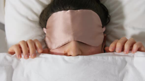 Woman with Eye Sleeping Mask in Bed Under Blanket