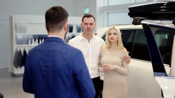 Portrait Couple Talking to Car Dealer in Dealership Discussing the Chosen Car