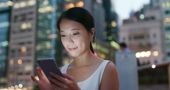 Woman work on mobile phone in city at night