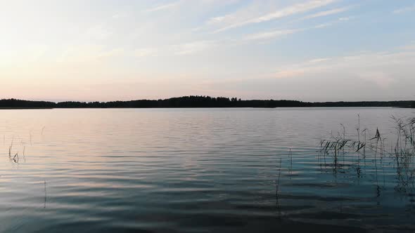 Fantastic Flight Over the Surface of the Lake in Nature at Sunset in Summer