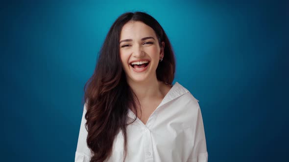 Cheerful Young Woman Smiling and Laughing Against Blue Background