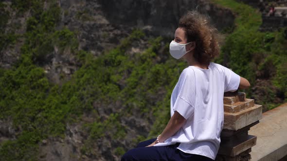 Side Shot of a Girl in a Face Mask Enjoying Beauty on the Nature Sitting on an Edge of the Viewing