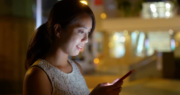 Asian woman use of mobile phone in the park at night