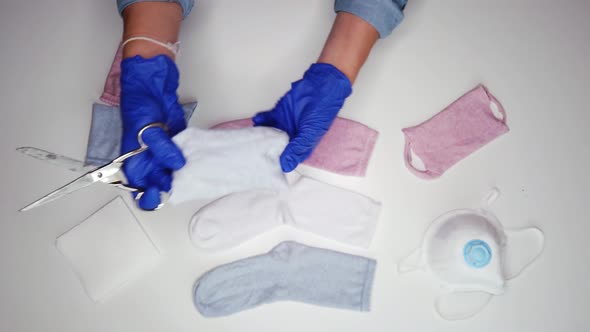 Unrecognizable woman in sterile gloves cutting sock to make mask