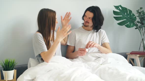 Young Man Making Marriage Proposal To Girl Putting Ring on Finger in Bed at Home