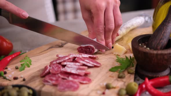 Woman Slicing Fuet Sausage with Knife at Domestic Kitchen